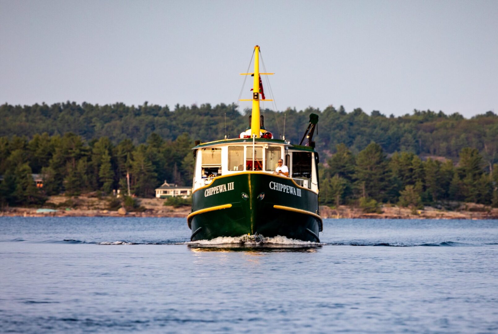 A boat is sailing on the water near some trees.