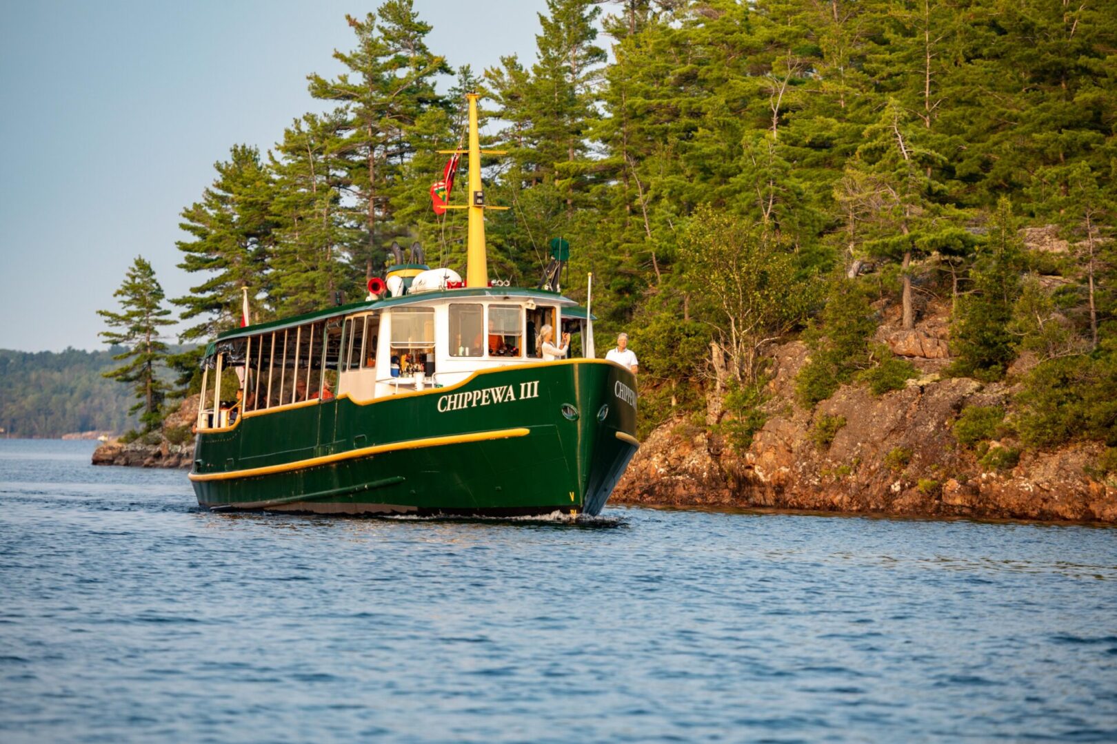 A boat is traveling on the water near some trees.